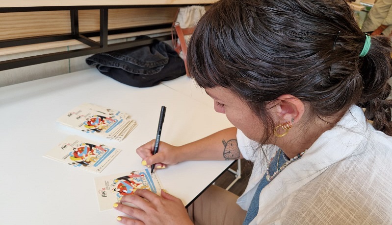 Laura Tova, asinando postais co deseño do cartel